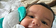 Miles is registered to the contest to win money with this photo: baby, bed, blanket, child, closeup, comfort, cuddling, cute, expression, face, happy, head, indoors, infant, person, plush_toy, portrait, skin, smiling, soft_toy