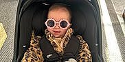 Lucia joined the competition — help win amazing prizes! baby, sunglasses, leopard_print, car_seat, plush_toy, blanket, indoor, carpet, door, sunlight, child, cute, fashion, toddler, smile, clothing, person, toy, seatbelt, home