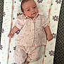 baby, infant, child, lying_down, changing_pad, floral_pattern, pink_clothing, striped_outfit, smiling, cute, small_hands, small_feet, carpet, pastel_colors, soft_texture, portrait, indoors, sleepwear, cozy, comfortable