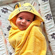 Lucia joined the competition — help win amazing prizes! baby, towel, yellow, smile, face, hood, animal_design, floral_pattern, changing_pad, cute, child, wrapped, soft_texture, indoor, person, infant, happy, lying_down, closeup, adorable