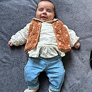 Rose a rejoint le concours — aidez-le/la à gagner de superbes lots ! baby, smiling, infant, clothing, orange_vest, white_blouse, blue_jeans, striped_socks, blanket, soft_texture, lying_down, cute, happy, indoor, portrait, child, small_hands, head, face, cozy