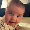 Rose participe au concours pour gagner de l'argent avec cette photo : baby, infant, tummy_time, smiling, cute, closeup, face, child, person, indoors, natural_light, soft_skin, cozy, patterned_clothing, happy, young, portrait, warm_light, curious, hands
