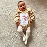 Rose a rejoint le concours — aidez-le/la à gagner de superbes lots ! baby, bright, card, carpet, child, clothing, cute, feet, floral_collar, hands, happy, indoor, infant, lying_down, person, portrait, smile, soft_texture, text, tights
