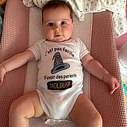 Rose participe au concours pour gagner de l'argent avec cette photo : adorable, baby, baby_clothes, blanket, changing_pad, child, clothing, cute, face, indoors, infant, lying_down, onesie, person, pink, portrait, soft_texture, text_on_clothing, white, wide_eyes