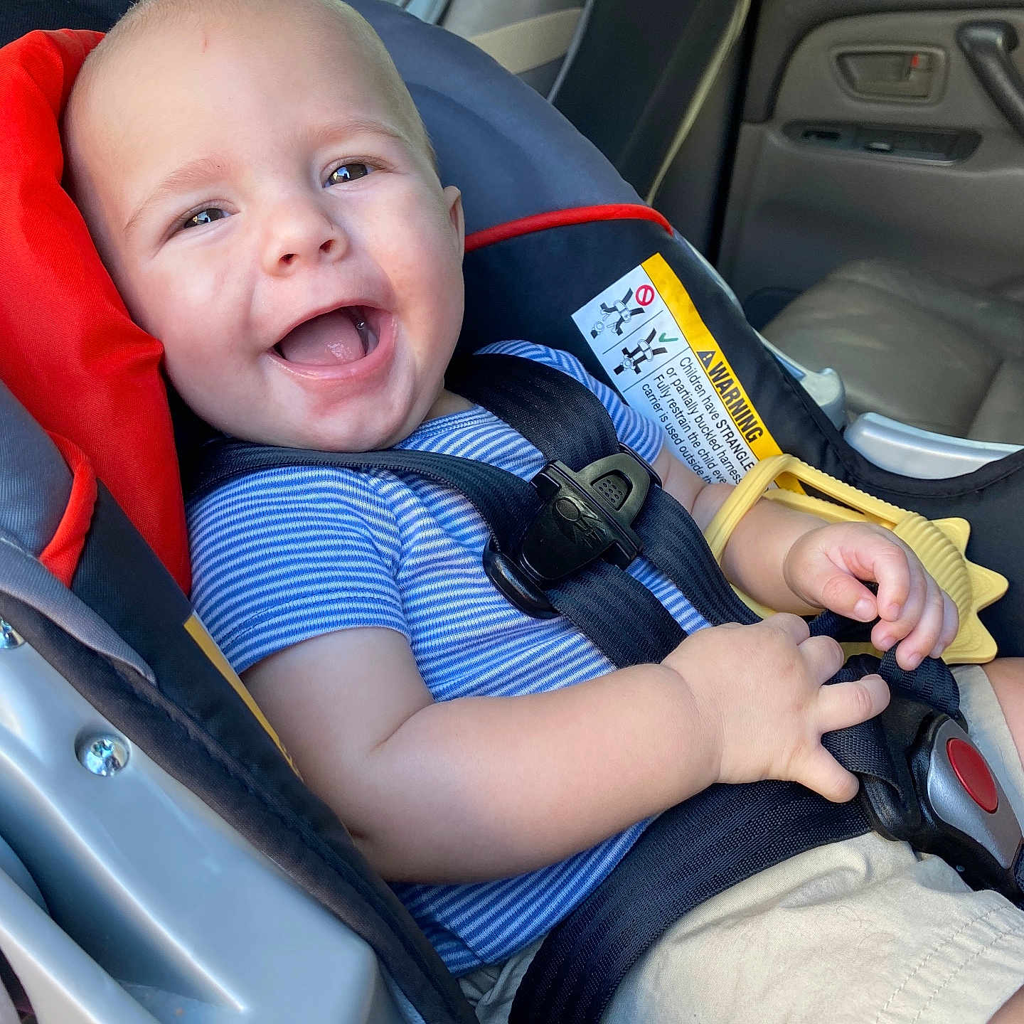 Leo Curtis is registered to the contest to win money with this photo: baby, blue_shirt, car_interior, car_seat, child, cute, daylight, hands, happy, infant, person, portrait, safety, seat, seatbelt, shorts, smile, teether, window, young