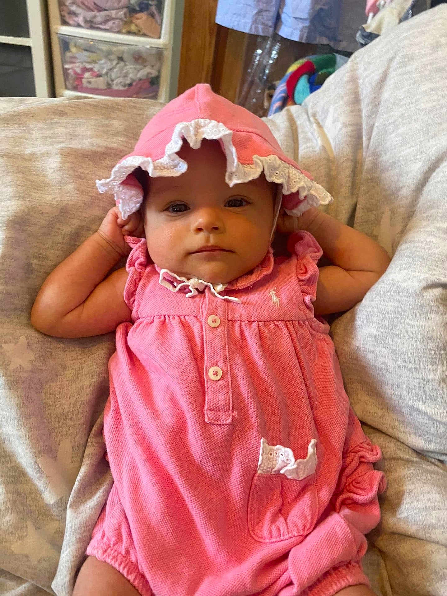 Freya joined the competition — help win amazing prizes! baby, infant, pink_clothing, bonnet, cute, portrait, child, relaxing, indoors, cushion, fabric, soft_lighting, person, small_hands, clothing, sitting, face, calm, young_child, home