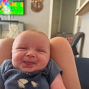 Braylon is registered to the contest to win money with this photo: baby, smiling, tongue_out, infant, person, clothing, sitting, legs, living_room, television, furniture, wall, door, decoration, home, cute, happy, skin, short_sleeves, indoor