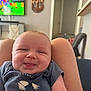 baby, smiling, tongue_out, infant, person, clothing, sitting, legs, living_room, television, furniture, wall, door, decoration, home, cute, happy, skin, short_sleeves, indoor