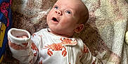 Cashton is registered to the contest to win money with this photo: baby, infant, onesie, crab_pattern, blanket, blue_eyes, hand, foot, pajamas, sleepwear, lying_down, indoor, child, cute, expression, soft_texture, cozy, person, face, apparel