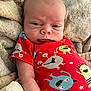 Cashton is registered to the contest to win money with this photo: baby, infant, onesie, red_clothing, monsters, blanket, soft_texture, face, expression, newborn, cute, child, person, indoors, lying_down, skin, head, small, cozy, sleepwear