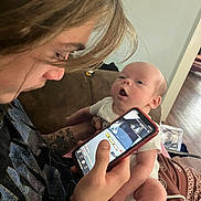 Cashton joined the competition — help win amazing prizes! baby, young_adult, person, smartphone, tattoo, couch, indoor, technology, holding, curly_hair, face, arm, clothing, phone_screen, expression, home, seated, casual, interaction, curiosity