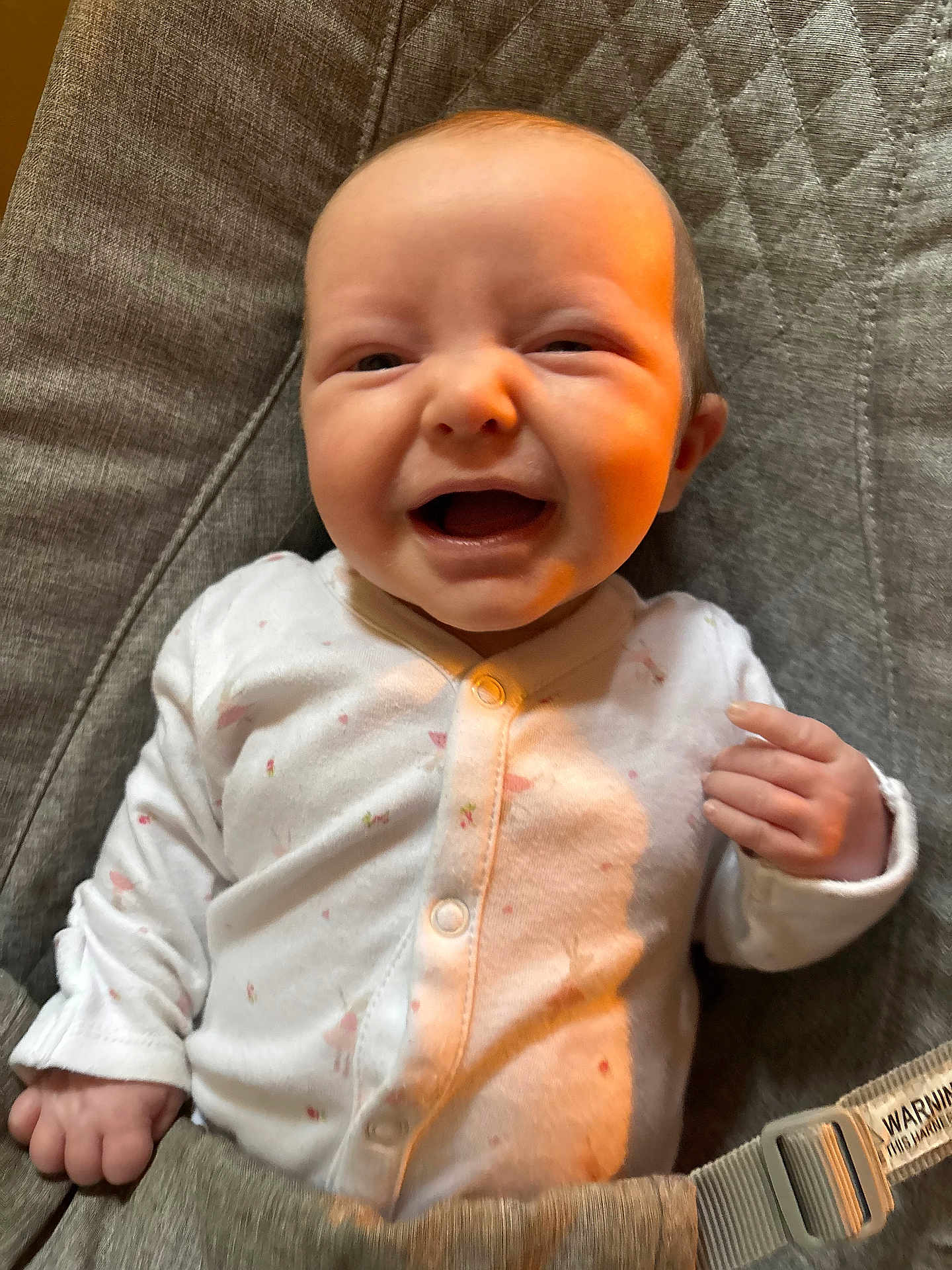 Penelope joined the competition — help win amazing prizes! baby, baby_seat, child, clothing, cushion, cute, expression, fist, gray_fabric, happy, human, indoor, infant, onesie, pink_pattern, portrait, seat, smile, white_clothing, young