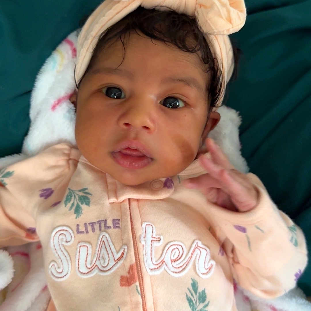 Jazelle is registered to the contest to win money with this photo: baby, bodypart, bonnet, cap, clothing, face, finger, hand, hat, head, hood, hoodie, knitwear, newborn, person, photography, portrait, skin, sweater, tattoo