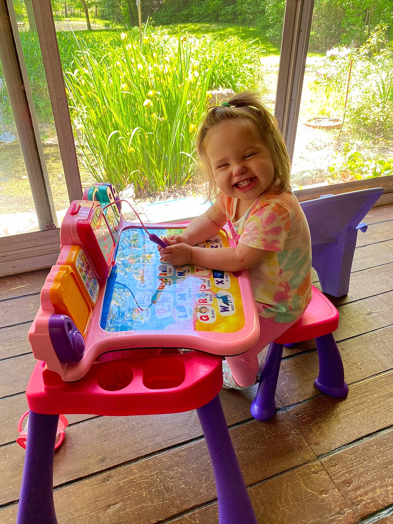 Sloane joined the competition — help win amazing prizes! baby_toddler_clothing, chair, child, facial_expression, fun, grass, green, happy, joy, leisure, magenta, outdoor_furniture, person, pink, plant, play, recreation, sitting, smile, toddler
