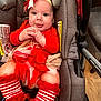 baby, car_seat, red_clothing, headband, bow, striped_socks, tulle, smiling, infant, cute, indoor, child, happy, person, seatbelt, holiday_outfit, floor, fabric, closeup, portrait