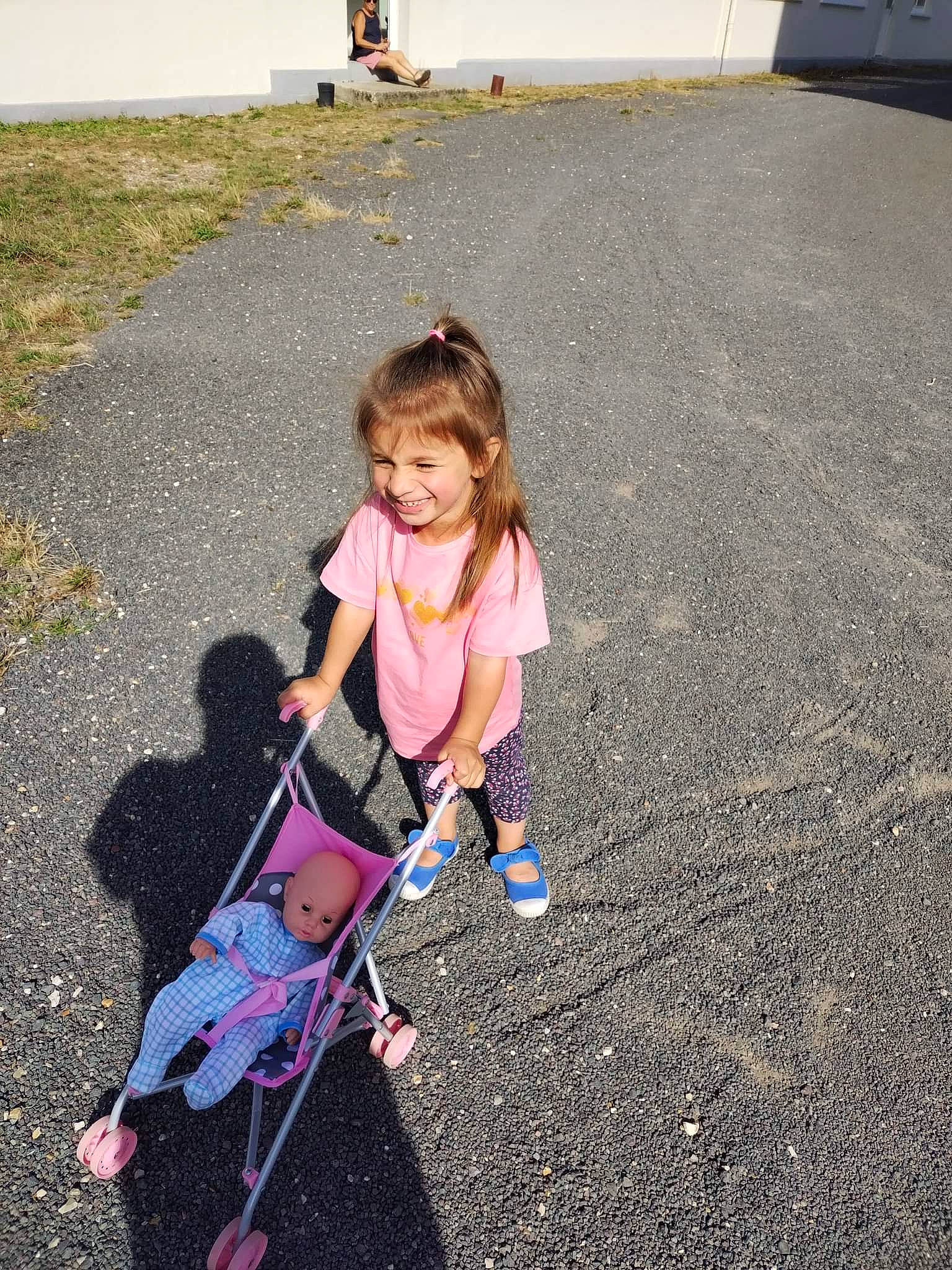 Léana participe au concours pour gagner de l'argent avec cette photo : asphalt, boot, child, fun, grass, headwear, human_settlement, joy, leisure, mammal, people, person, recreation, road, road_surface, shadow, sidewalk, sitting, smile, sneakers