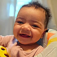 Evonna joined the competition — help win amazing prizes! baby, child, closeup, clothing, colorful, curly_hair, cute, face, happy, indoor, infant, joyful, natural_light, padded_chair, person, portrait, seated, smiling, window, young_child