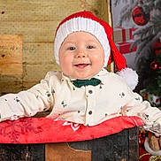 émile a rejoint le concours — aidez-le/la à gagner de superbes lots ! baby, celebration, child, christmas, clothing, cute, decoration, festive, gift, happy, holiday, indoors, portrait, present, red, santa_hat, smile, toy, tree, white