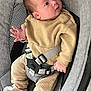 baby, infant, child, seat, car_seat, straps, clothing, beige_outfit, footwear, soft_toys, face, hand, curious_expression, indoor, fabric, safety_harness, head, person, cute, comfort