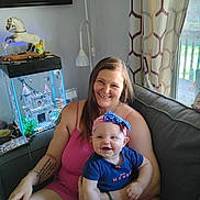 Dawn joined the competition — help win amazing prizes! baby, castle_decoration, couch, curtains, family, figurine, fish_tank, happy, headband, holding, horse, indoor, living_room, natural_light, person, pink_dress, smiling, tattoo, window, woman