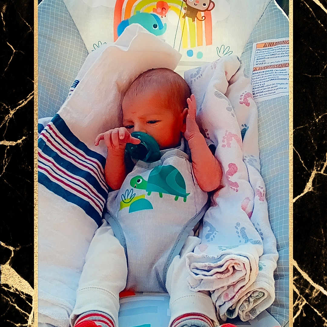 Gage is registered to the contest to win money with this photo: newborn, baby, infant, pacifier, baby_seat, blanket, socks, onesie, dinosaur_print, rainbow, monkey, toy, baby_clothing, portrait, cute, resting, indoors, child, soft_toys, colorful
