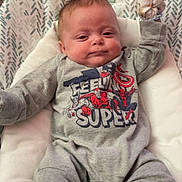 Nicholas joined the competition — help win amazing prizes! baby, bouncer, carpet, child, clothing, cozy, cute, indoor, infant, lying_down, mittens, onesie, patterned_pad, pillow, portrait, raised_arm, smile, socks, soft_lighting, superhero_print