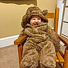baby, child, smile, fuzzy_clothing, onesie, brown, rocking_chair, wooden_chair, indoor, carpet, happy, cute, toddler, hood, ears, seated, infant, cozy, playful, home