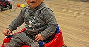 Elijah joined the competition — help win amazing prizes! toddler, child, toy_car, red, grey_hoodie, indoor, wooden_floor, toys, balls, smiling, happy, playtime, living_room, furniture, bench, refrigerator, kitchen, home, cute, seat