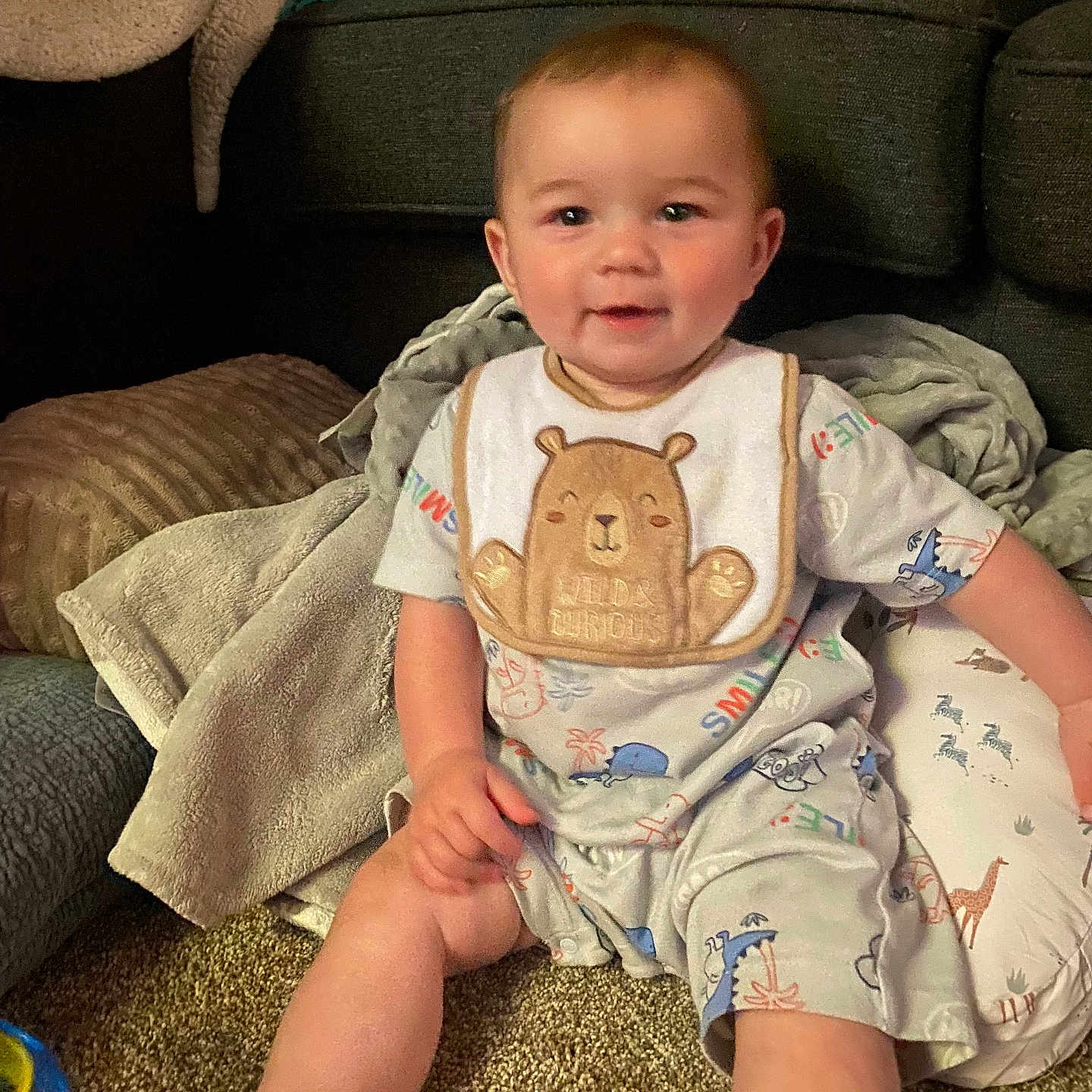 Elijah joined the competition — help win amazing prizes! animal_print, baby, bib, blanket, carpet, child, cozy, cushion, cute, floor, happy, home, indoor, infant, pajamas, person, playful, sitting, smiling, soft_lighting