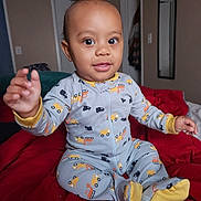 Uriah is registered to the contest to win money with this photo: baby, bed, bedroom, bodypart, clothing, couch, face, finger, furniture, hand, happy, head, indoors, pajamas, person, photography, portrait, room, sitting, smile