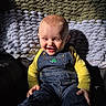 Walker is registered to the contest to win money with this photo: baby, child, smiling, denim_overalls, yellow_shirt, sunlight, blanket, happy, indoor, portrait, cute, infant, sitting, cozy, texture, face, person, clothing, young_child, joyful
