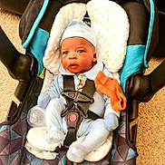 Damian joined the competition — help win amazing prizes! baby, blue_clothing, car_harness, car_seat, car_seat_buckle, car_seat_handle, car_seat_padding, car_seat_strap, carpet, child, cute, hat, indoor, infant, orange_cloth, pacifier, person, seated, secure, young