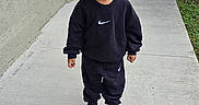 Amelia-Allena joined the competition — help win amazing prizes! child, toddler, standing, outdoor, sidewalk, concrete, portrait, smiling, happy, athletic_wear, black_clothing, sneakers, sweatshirt, pants, curly_hair, hairstyle, backyard, fence, gate, residential