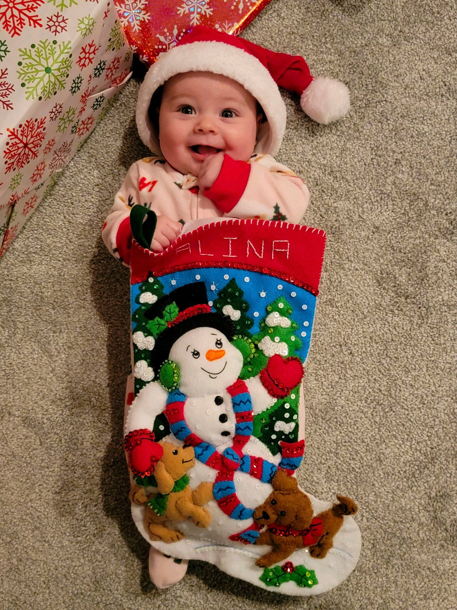 Alina is registered to the contest to win money with this photo: baby_toddler_clothing, christmas, clothing, costume_hat, dress, event, face, happy, headgear, headwear, holiday, human_body, joy, outerwear, pattern, person, red, sleeve, smile, snowman