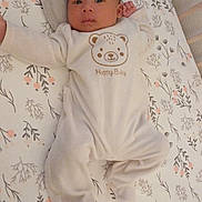 Sahel participe au concours pour gagner de l'argent avec cette photo : baby, infant, crib, onesie, pillow, face, person, sleepwear, cute, pattern, floral, bed, soft, calm, lying_down, indoors, child, newborn, head, blanket