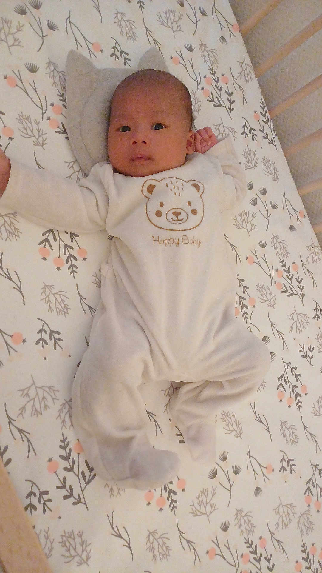 Sahel participe au concours pour gagner de l'argent avec cette photo : baby, infant, crib, onesie, pillow, face, person, sleepwear, cute, pattern, floral, bed, soft, calm, lying_down, indoors, child, newborn, head, blanket