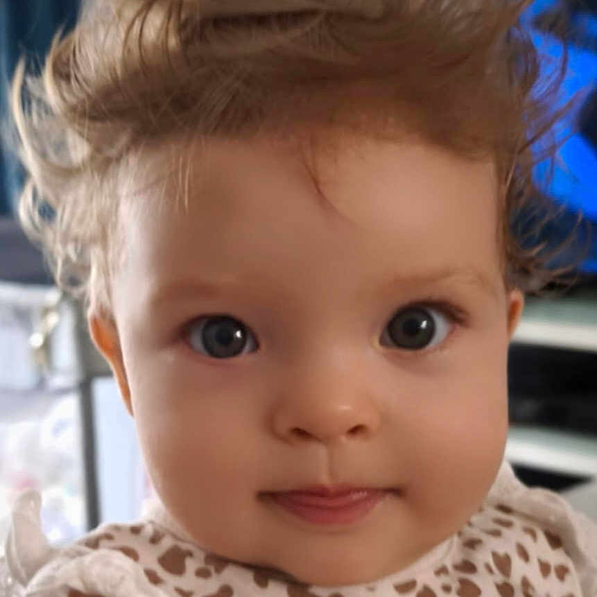 Mia participe au concours pour gagner de l'argent avec cette photo : apparel, baby, blue_eyes, child, closeup, curly_hair, cute, dress, expression, face, hair, heart_pattern, indoor, infant, pattern, person, portrait, smile, soft_lighting, young_child