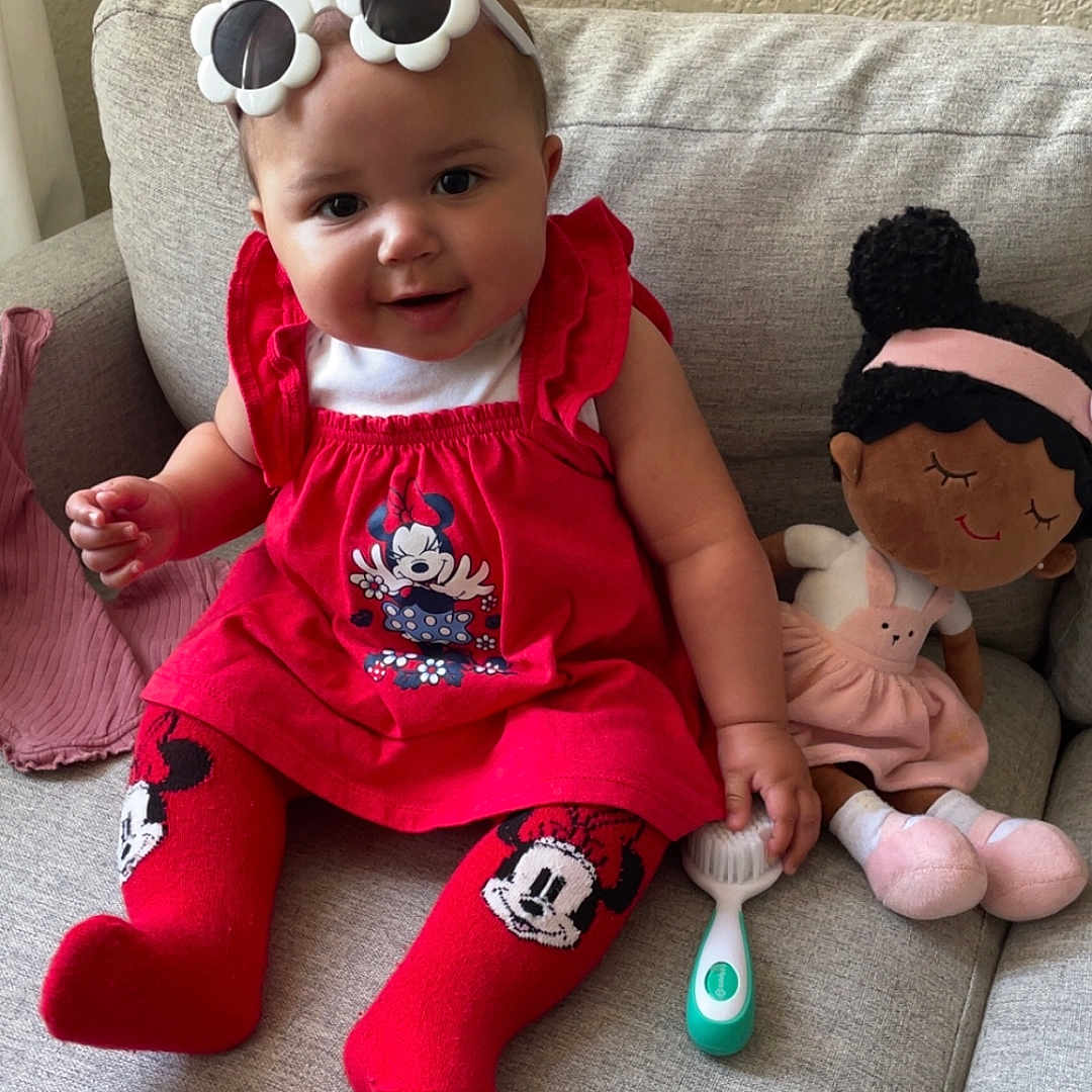 Delilah joined the competition — help win amazing prizes! baby, baby_brush, child, couch, cozy, cute, doll, hair_accessory, homedecor, indoor, infant, minnie_mouse, playful, portrait, red_clothing, sitting, smiling, stockings, sunglasses, toy