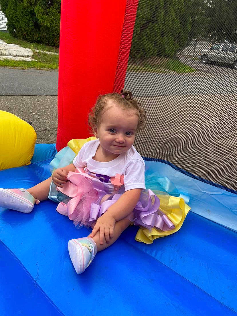 Aria is registered to the contest to win money with this photo: blue, bounce_house, child, chute, fun, grass, green, happy, human_settlement, inflatable, joy, leisure, outdoor_play_equipment, outdoor_recreation, person, plant, playground, public_space, recreation, smile