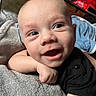 Elias joined the competition — help win amazing prizes! baby, smile, face, infant, towel, arm, skin, clothing, black_shirt, happy, eyes, hand, indoors, person, cute, portrait, resting, expression, closeup, newborn