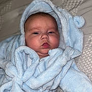 Oakley is registered to the contest to win money with this photo: baby, blanket, blue_robe, child, chubby_cheeks, cozy, cute, expression, face, hood, indoors, infant, lying_down, newborn, person, portrait, robe, skin, sleepwear, soft_texture