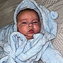 baby, blanket, blue_robe, child, chubby_cheeks, cozy, cute, expression, face, hood, indoors, infant, lying_down, newborn, person, portrait, robe, skin, sleepwear, soft_texture