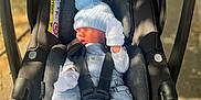 Oakley is registered to the contest to win money with this photo: baby, car_seat, infant, blue_hat, mittens, pacifier_clip, outdoor, sunlight, black_car_seat, clothing, newborn, socks, cute, sleeping, child, safety_harness, portrait, baby_accessory, infant_clothing, cozy