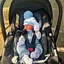 baby, car_seat, infant, blue_hat, mittens, pacifier_clip, outdoor, sunlight, black_car_seat, clothing, newborn, socks, cute, sleeping, child, safety_harness, portrait, baby_accessory, infant_clothing, cozy