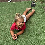 Kayden participe au concours pour gagner de l'argent avec cette photo : child, smiling, grass, artificial_turf, barefoot, red_shirt, shorts, outdoor, playful, happy, young, person, footwear, sandals, dirt, grass_patch, casual, summer, childhood, relaxed