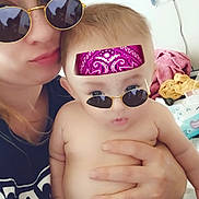 Bella is registered to the contest to win money with this photo: adult, baby, diaper, indoor, person, hand, glasses, bandana, mirror, reflection, casual, holding, skin, face, freckles, clothing, towel, household, portrait, closeup