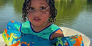 Bronx joined the competition — help win amazing prizes! child, curly_hair, floatation_device, dinosaur_pattern, swimwear, boat, lake, water, trees, outdoor, summer, sunlight, nature, young_child, sitting, expression, water_safety, recreation, vacation, daytime