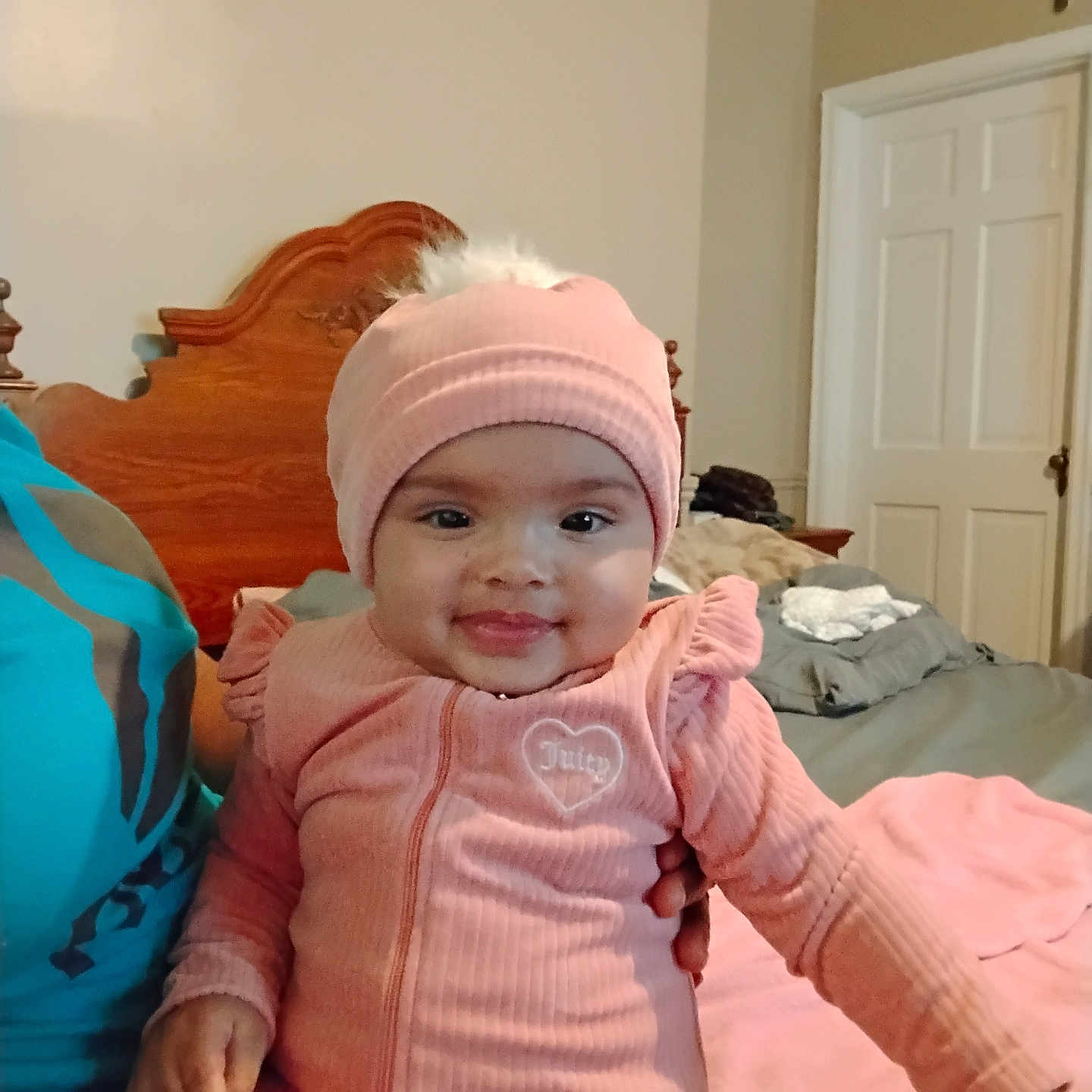 Akirra joined the competition — help win amazing prizes! baby, bed, bedroom, child, cozy, cute, dressed, happy, hat, human, indoor, infant, joyful, person, pink_clothing, portrait, seated, smile, warm_clothing, wooden_headboard