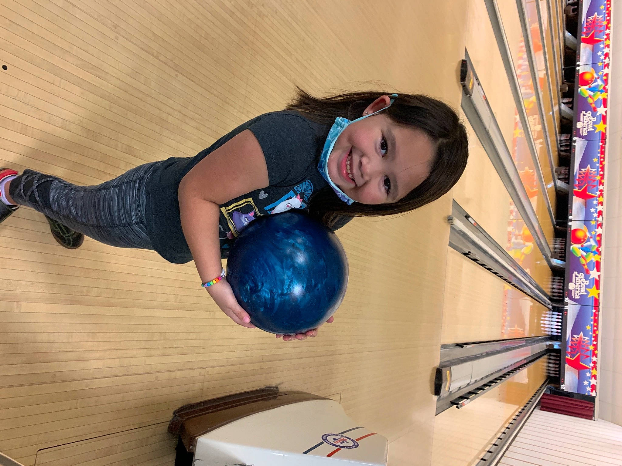 Kyleigh is registered to the contest to win money with this photo: art, balance, ball, bowling_equipment, child, elbow, electric_blue, flooring, fun, hardwood, human_leg, joy, knee, leg, leisure, person, recreation, smile, sports_equipment, sportswear