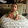 Lucas Harrison is registered to the contest to win money with this photo: baby, child, teething_toy, pillow, elephant_pattern, couch, living_room, carpet, baby_lotion, green_shirt, infant, surprised_expression, hand, face, sitting, furniture, indoors, toy, person, cute